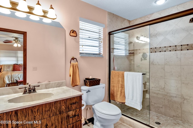 bathroom featuring toilet, a shower with door, ceiling fan, and vanity