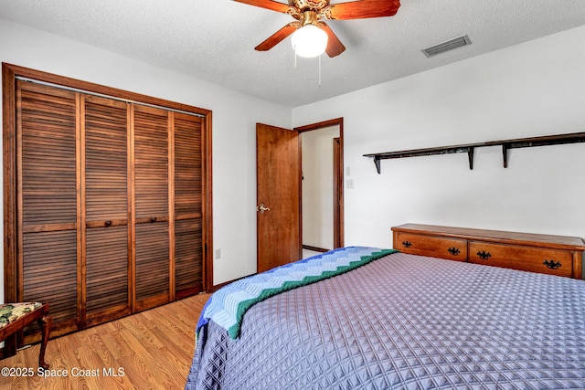 bedroom with ceiling fan, a closet, a textured ceiling, and hardwood / wood-style flooring