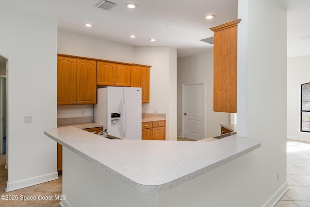 kitchen with kitchen peninsula, white fridge with ice dispenser, light tile patterned floors, and sink