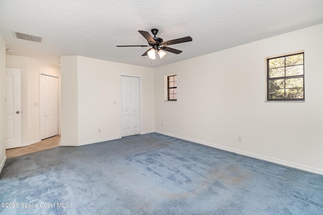 carpeted empty room featuring ceiling fan and a textured ceiling