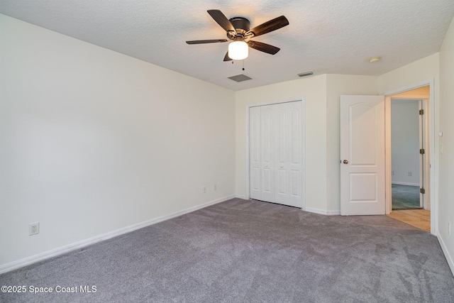 unfurnished bedroom featuring ceiling fan, a closet, light colored carpet, and a textured ceiling