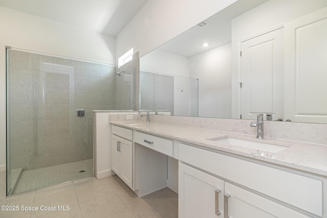 bathroom with tile patterned floors, vanity, and tiled shower