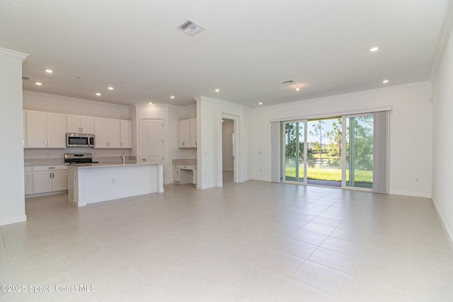 kitchen with white cabinetry, appliances with stainless steel finishes, a center island with sink, light tile patterned flooring, and ornamental molding