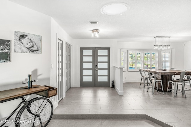 entrance foyer featuring a textured ceiling, french doors, and tile patterned floors