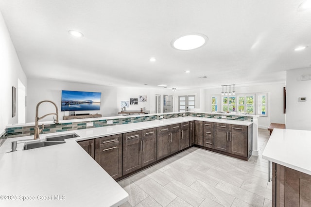 kitchen featuring kitchen peninsula, dark brown cabinetry, and sink