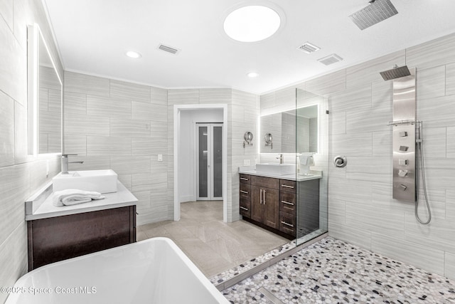 bathroom with tile walls, shower with separate bathtub, and vanity