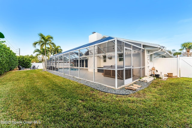 back of house featuring a lawn, a lanai, a fenced in pool, and a patio area