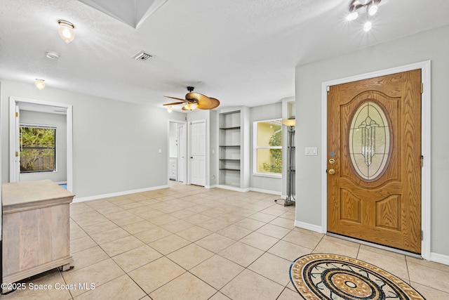 tiled entryway with a textured ceiling, ceiling fan, and a wealth of natural light