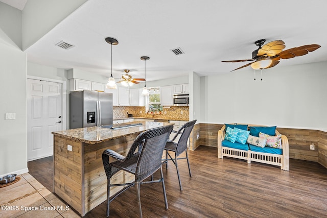 kitchen featuring white cabinetry, a center island, hanging light fixtures, light stone countertops, and appliances with stainless steel finishes