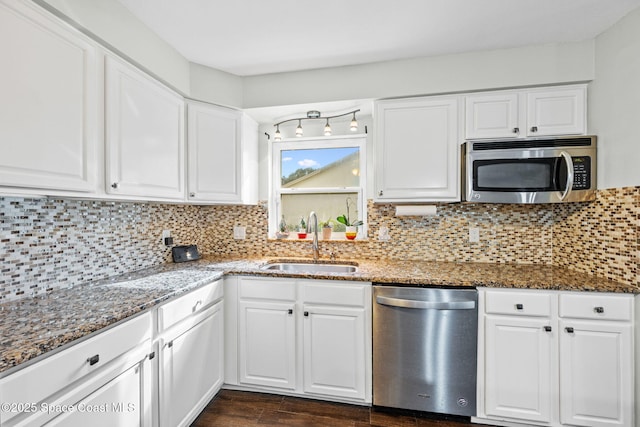 kitchen featuring dark stone countertops, stainless steel appliances, sink, white cabinetry, and backsplash