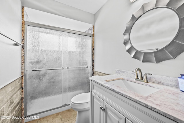 bathroom with toilet, tile patterned flooring, a shower with shower door, and vanity