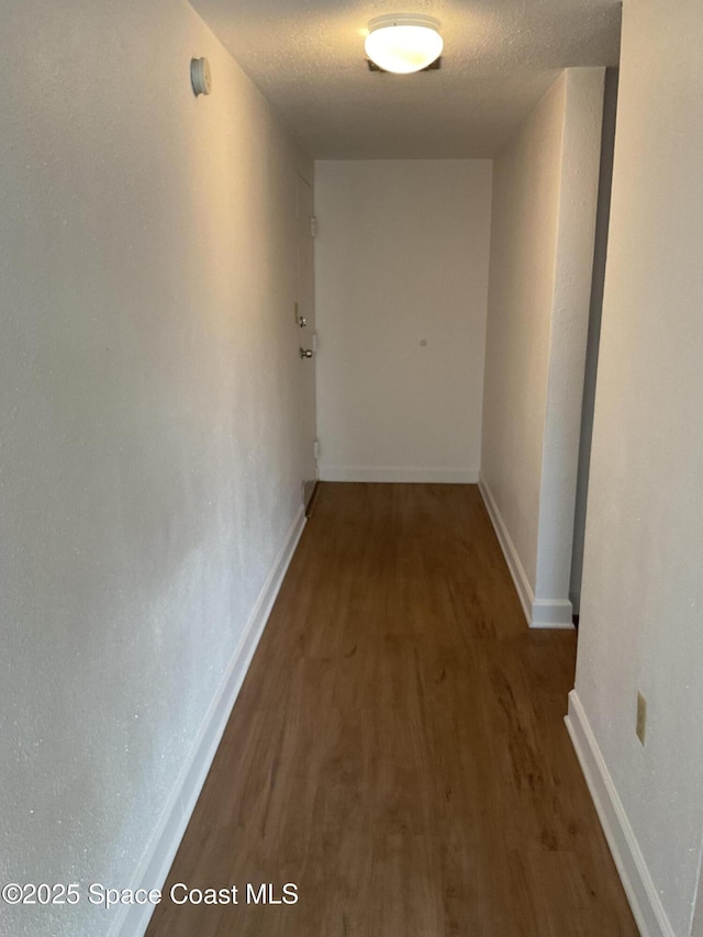 corridor with dark hardwood / wood-style floors and a textured ceiling