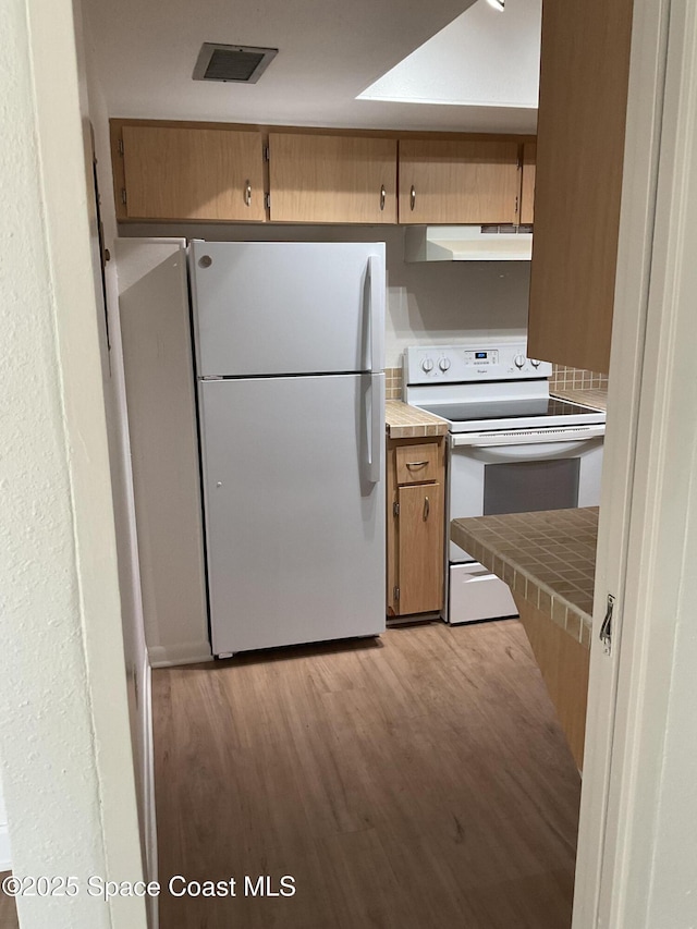 kitchen with tile counters, white appliances, and light hardwood / wood-style flooring