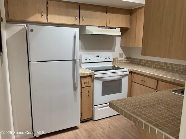 kitchen with tile counters, white appliances, and light hardwood / wood-style flooring