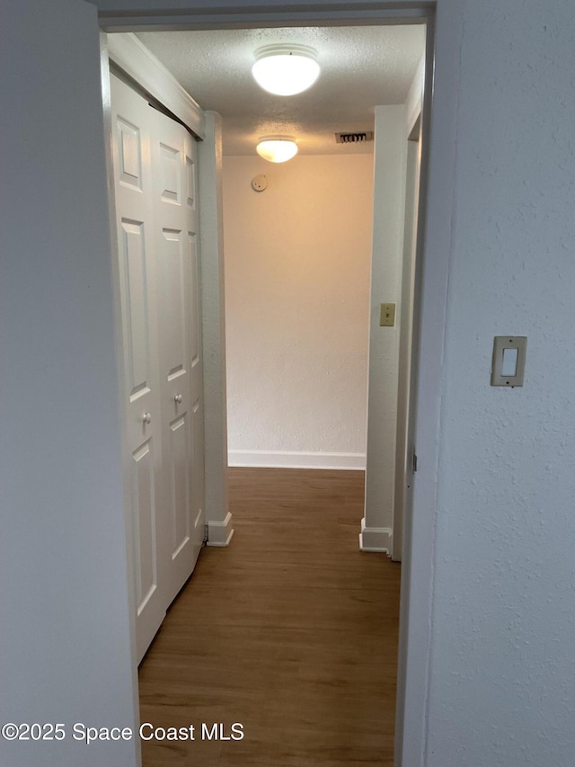 hall with dark hardwood / wood-style flooring and a textured ceiling