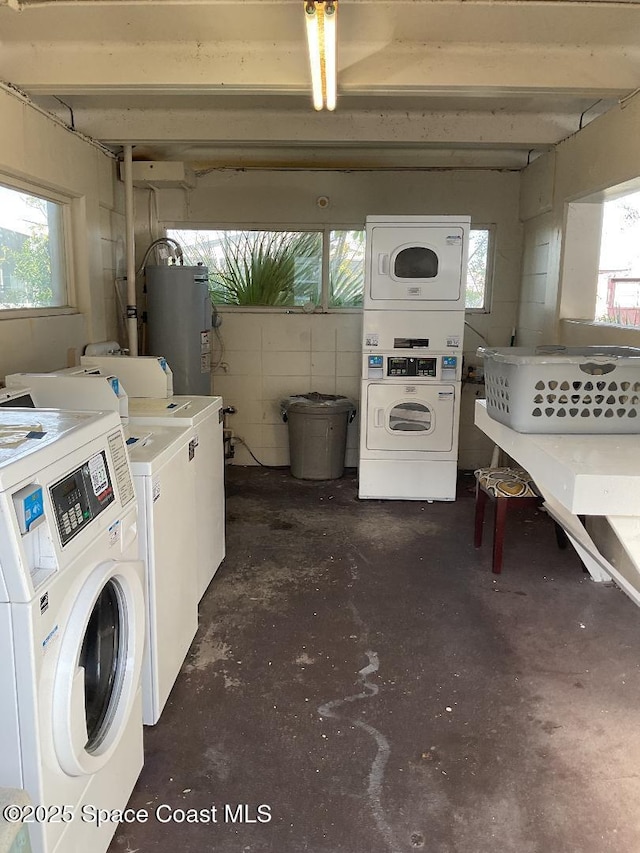 laundry area featuring plenty of natural light, washing machine and dryer, stacked washer / drying machine, and gas water heater