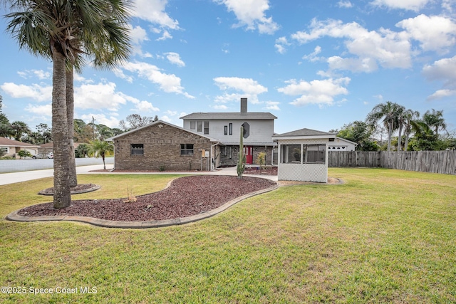 rear view of house with a lawn, a patio area, and a sunroom