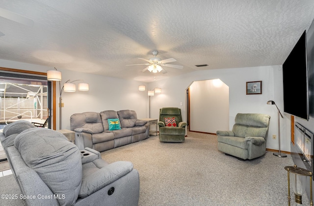 living room featuring a textured ceiling, ceiling fan, lofted ceiling, and carpet floors