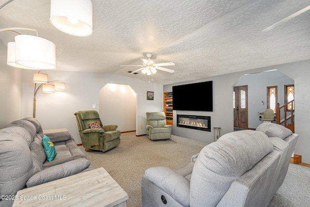 living room featuring ceiling fan, vaulted ceiling, carpet, and a textured ceiling