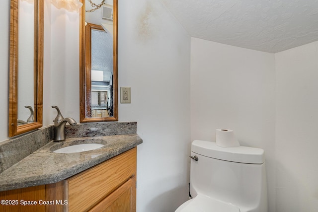 bathroom featuring a textured ceiling, toilet, and vanity