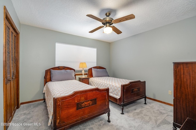 carpeted bedroom with ceiling fan, a textured ceiling, and a closet