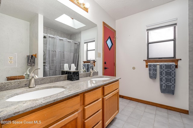 bathroom featuring walk in shower, vanity, a skylight, and a textured ceiling