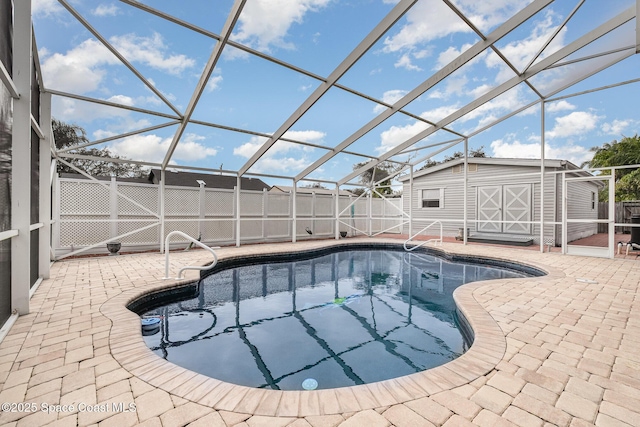 view of pool with glass enclosure, a patio area, and a storage unit