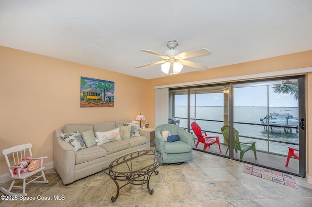 living room featuring ceiling fan and a water view