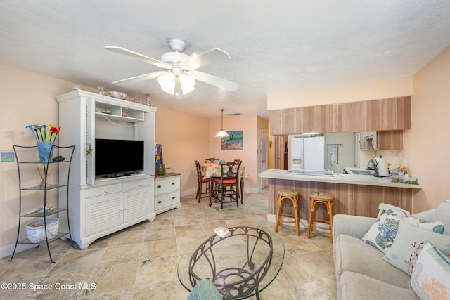 living room with ceiling fan and a textured ceiling