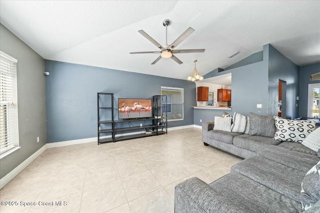 tiled living room with ceiling fan with notable chandelier and vaulted ceiling