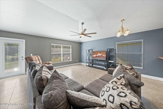 living room featuring ceiling fan with notable chandelier, light tile patterned flooring, and a textured ceiling