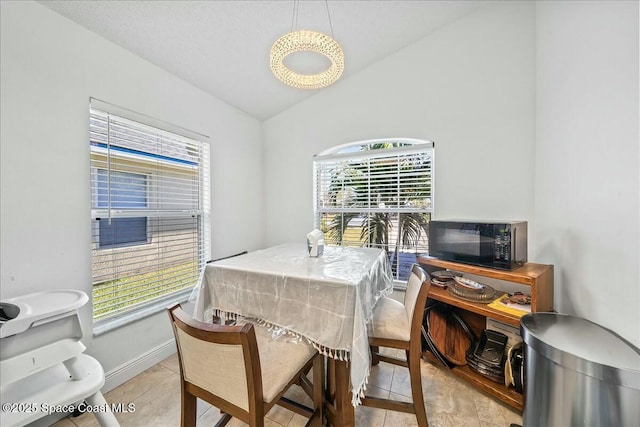 dining area with lofted ceiling, light tile patterned floors, and a wealth of natural light