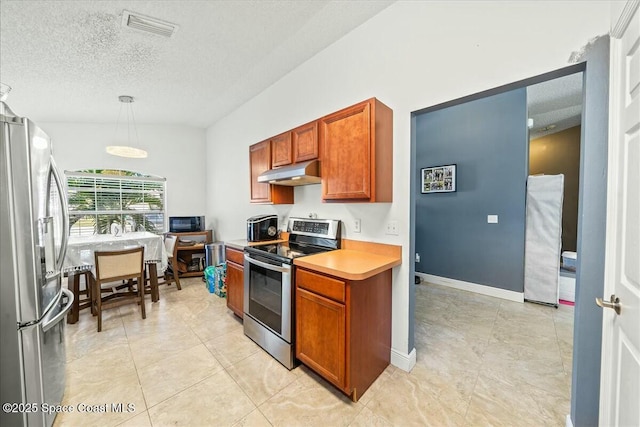 kitchen with pendant lighting, light tile patterned flooring, stainless steel appliances, and a textured ceiling