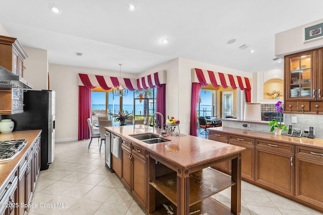 kitchen featuring sink, appliances with stainless steel finishes, pendant lighting, light stone countertops, and backsplash