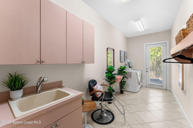 washroom with sink, light tile patterned floors, washing machine and dryer, and cabinets