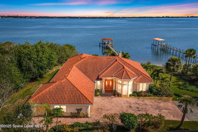 aerial view at dusk featuring a water view