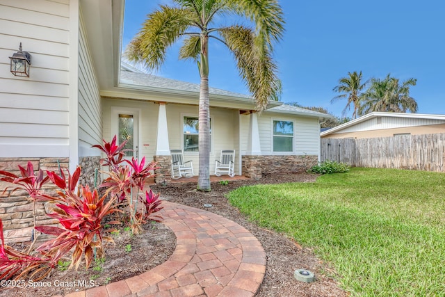 view of exterior entry featuring covered porch and a yard