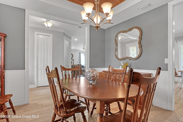 dining space with crown molding, a chandelier, and light hardwood / wood-style floors