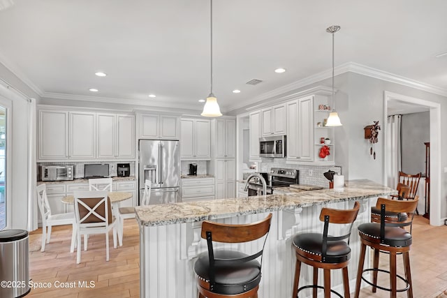 kitchen featuring tasteful backsplash, pendant lighting, kitchen peninsula, white cabinetry, and stainless steel appliances