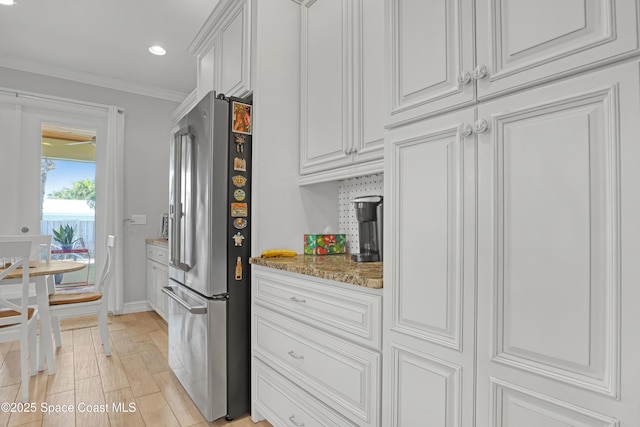 kitchen featuring light stone countertops, ornamental molding, white cabinets, and high quality fridge