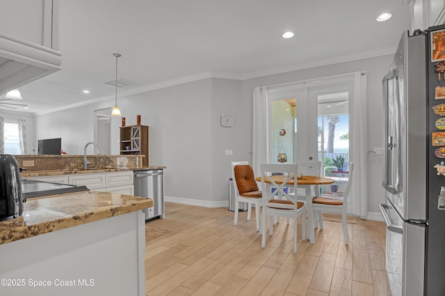 kitchen featuring crown molding, hanging light fixtures, appliances with stainless steel finishes, white cabinets, and light stone counters