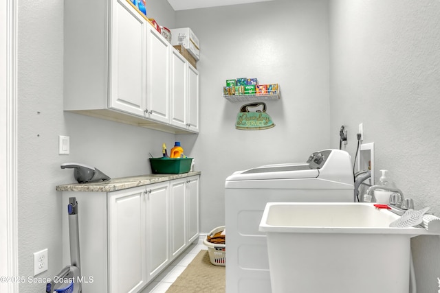 washroom with cabinets, light tile patterned floors, sink, and washing machine and clothes dryer