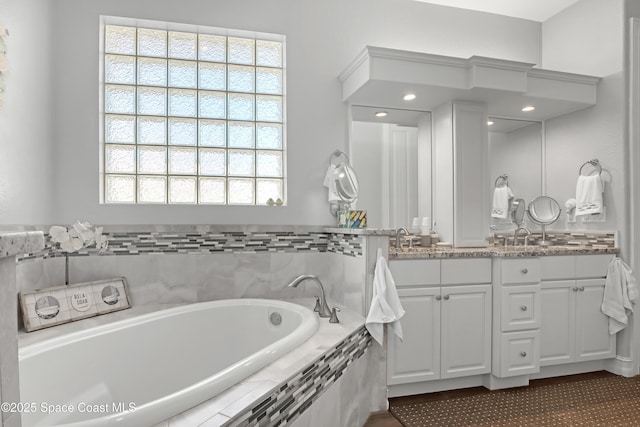 bathroom featuring tiled bath, a wealth of natural light, and vanity