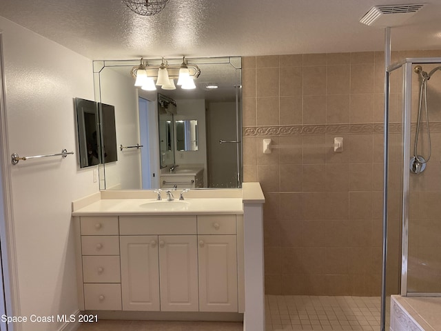 bathroom with a textured ceiling, an enclosed shower, and vanity