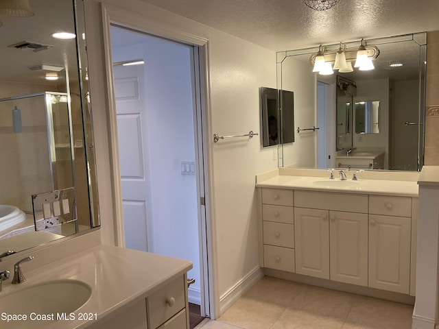 bathroom with a textured ceiling, tile patterned flooring, a shower with shower door, and vanity