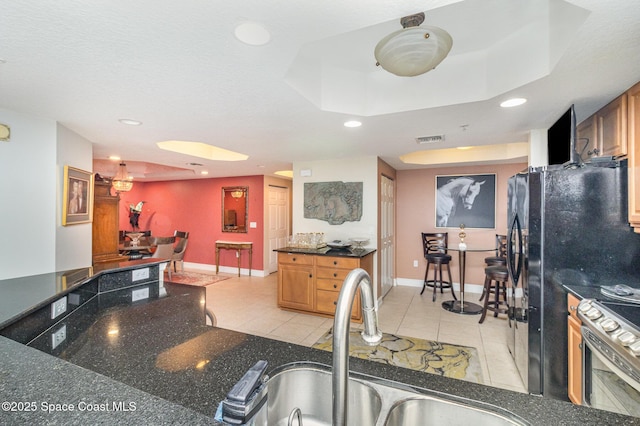 kitchen featuring light tile patterned floors, a tray ceiling, stainless steel electric stove, a textured ceiling, and sink