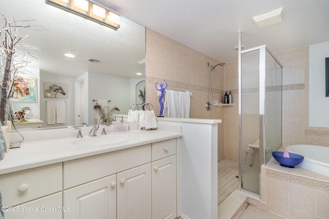 bathroom featuring a textured ceiling, vanity, and separate shower and tub