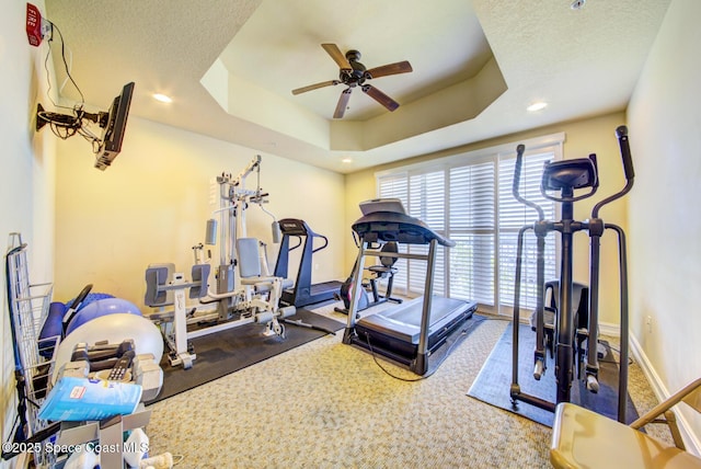 workout room with ceiling fan, carpet, a tray ceiling, and a textured ceiling