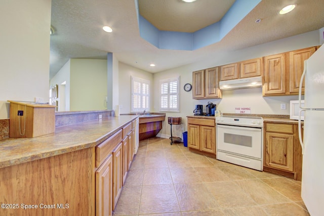 kitchen featuring light tile patterned floors, sink, white appliances, and a tray ceiling