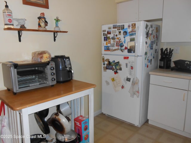 kitchen featuring white cabinetry and white fridge